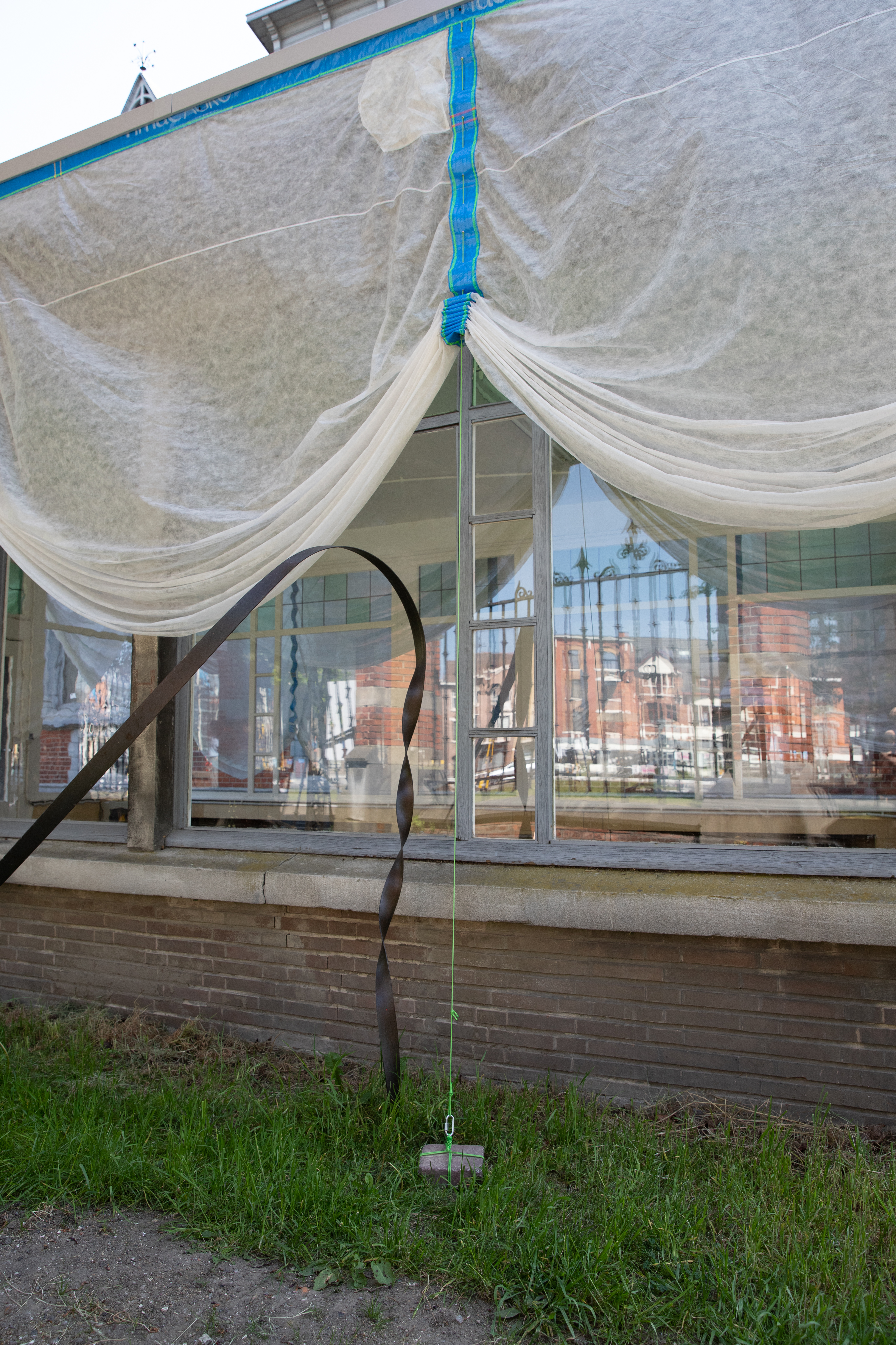 "Underbelly" view of the collective exhibition. Frost protection fabric, plastic seeds bags, and bricks found on site. 
© Frederik Aerts